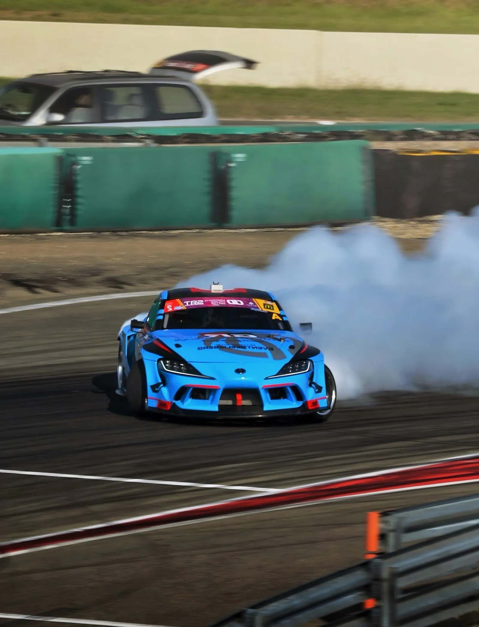 Auto da drift blu che solleva fumo dalle gomme su una pista