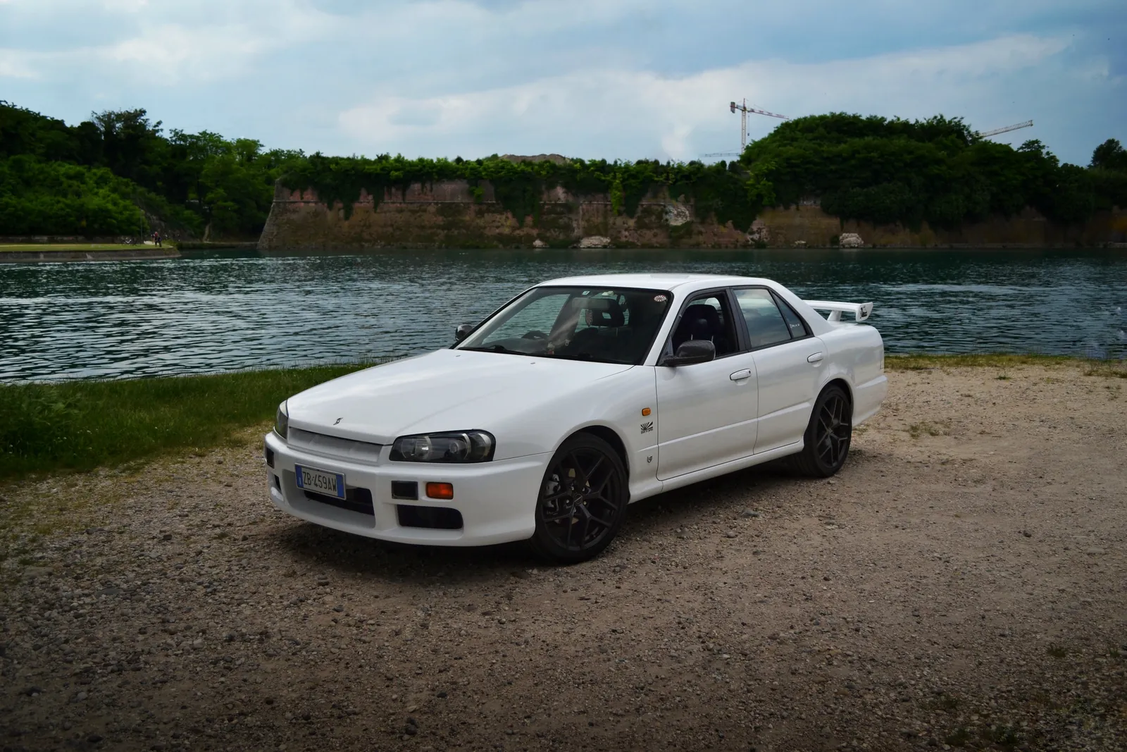 Nissan Skyline berlina bianca parcheggiata accanto a un lago
