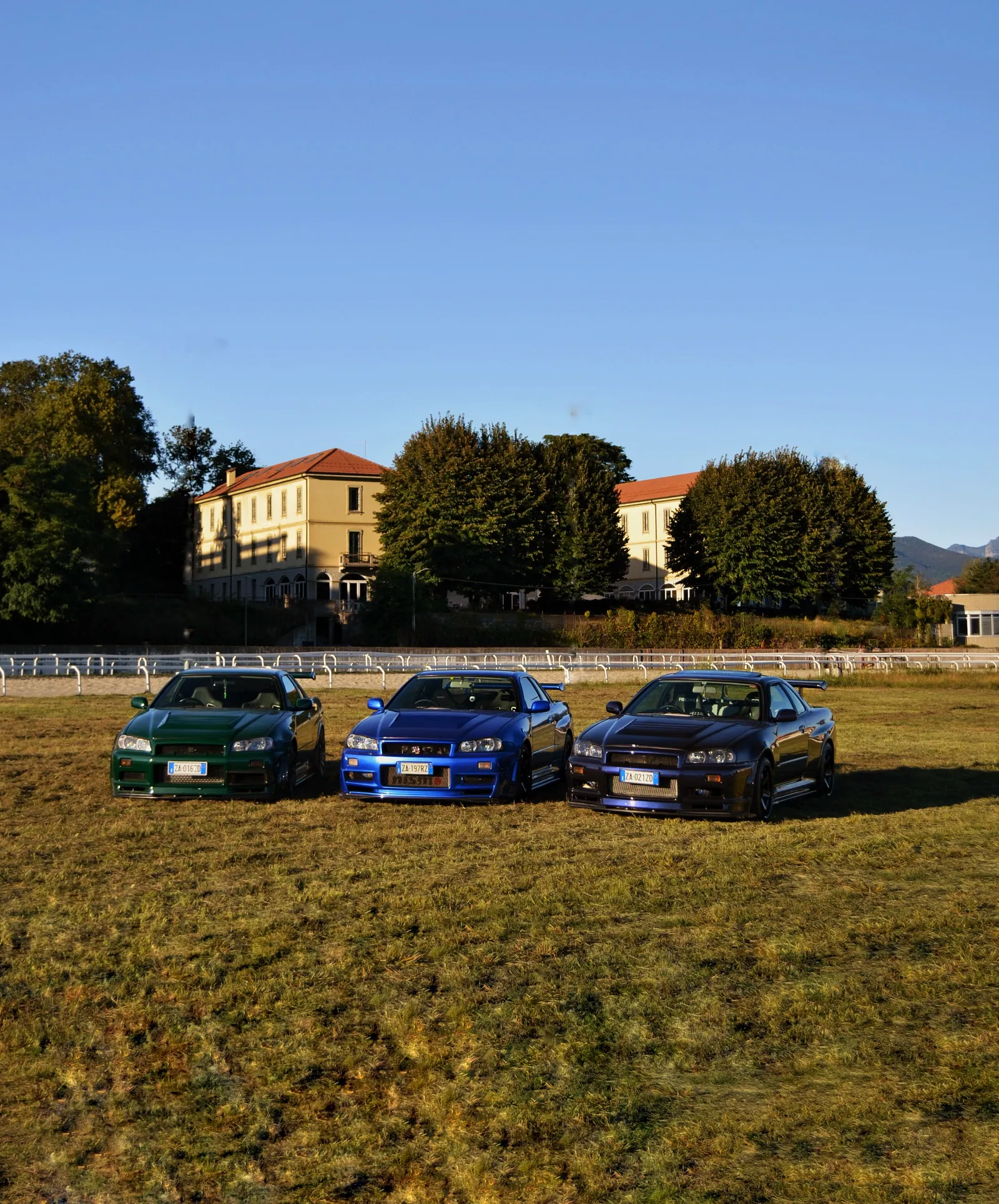 Tre Nissan Skyline GT-R parcheggiate in un prato davanti a una villa