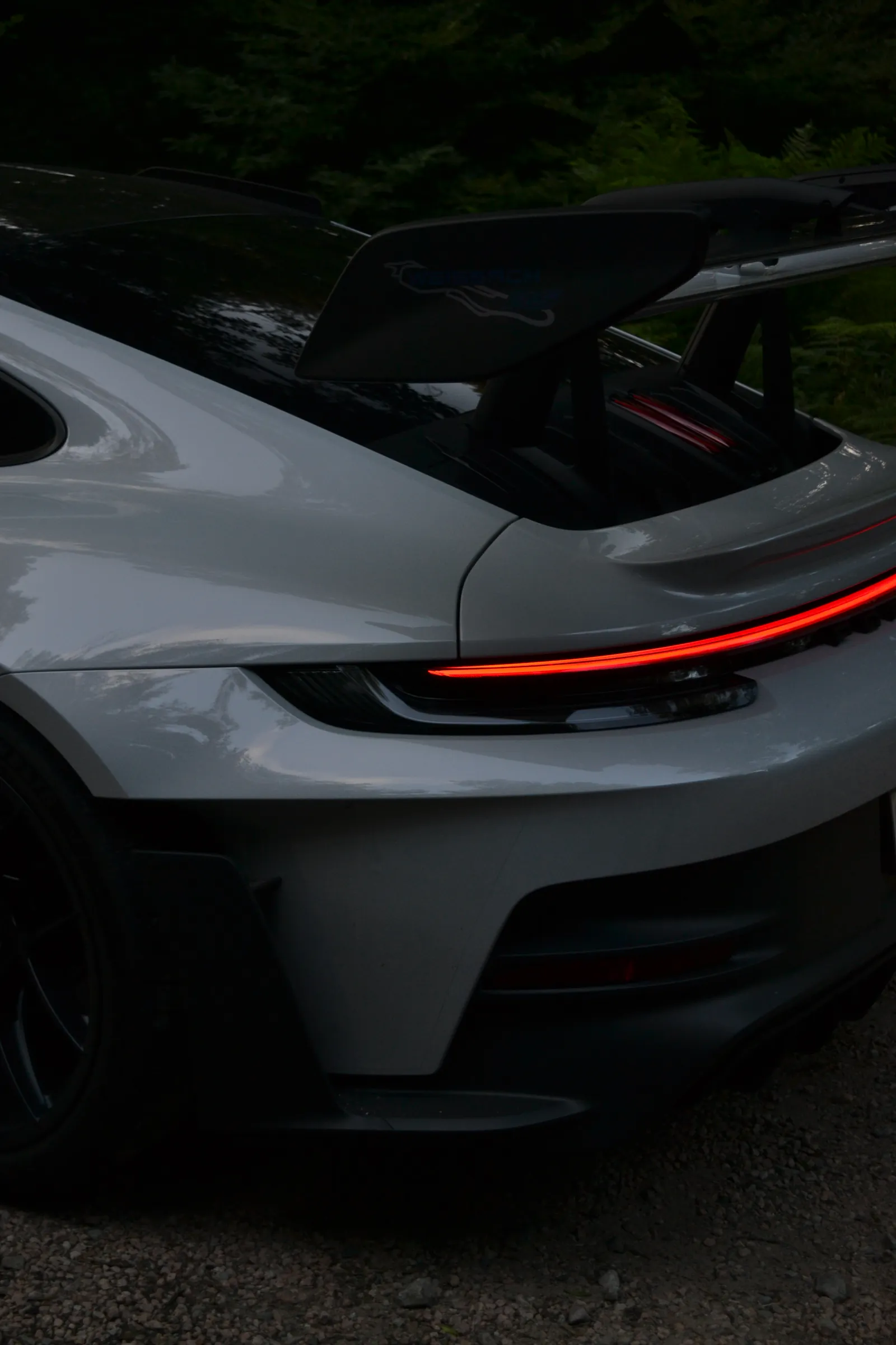 Posteriore di una Porsche 911 GT3 grigia con alettone alzato e barra luminosa rossa