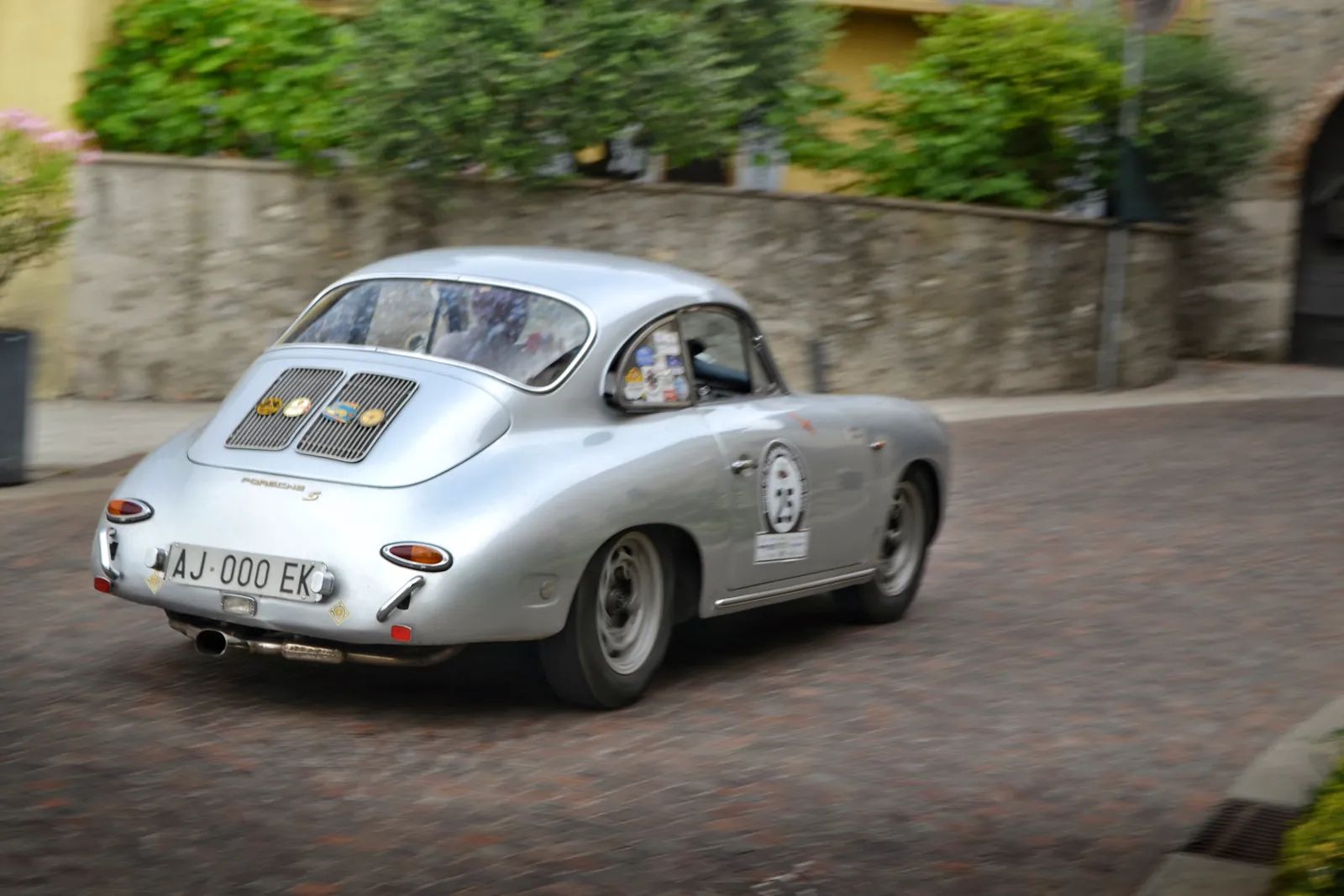 Porsche 356 d'epoca argento in un paese durante un rally storico